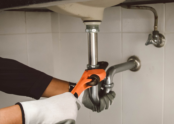 Plumber working on pipes under a sink